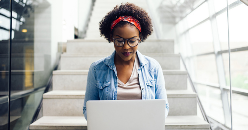 Woman sitting on stairs, working on a laptop