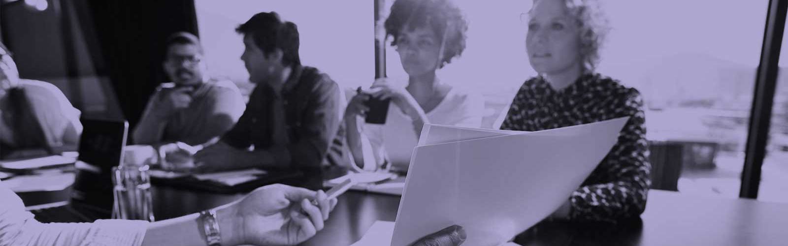 People talking in a meeting and holding paper in their hands