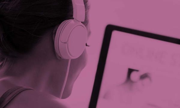 A person wearing headphones studying at a computer