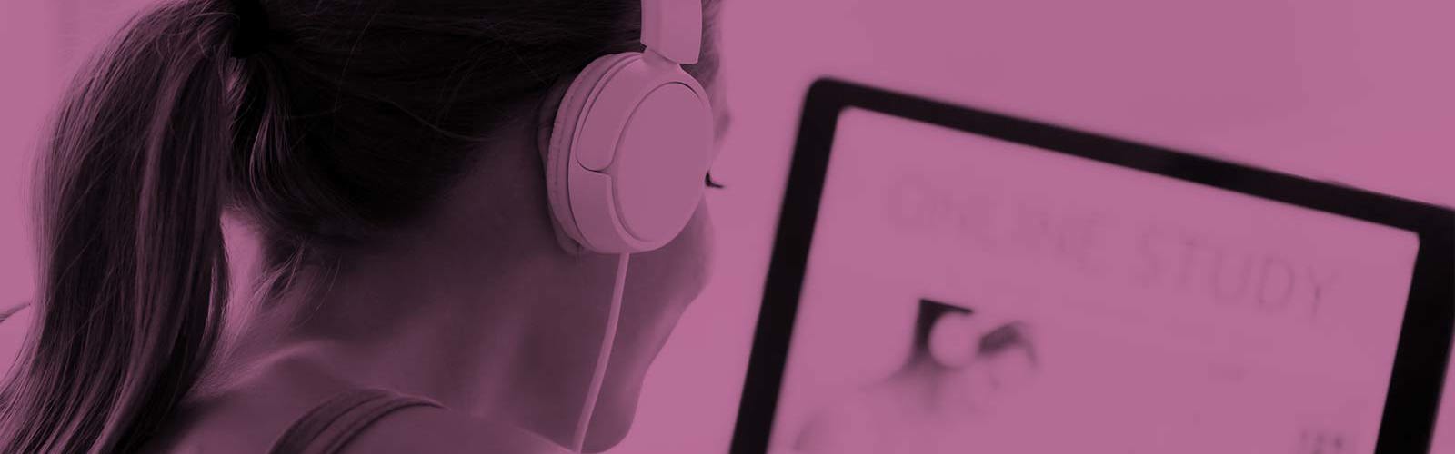A person wearing headphones studying at a computer
