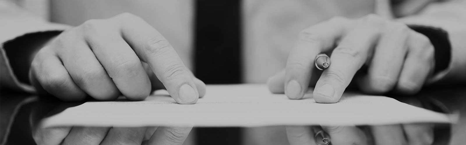 Close up of some hands holding a pen poised over a piece of paper