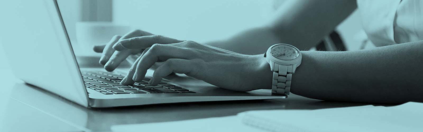 Hands typing on laptop at workplace 