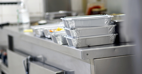 An industrial kitchen with takeaway containers on the counter