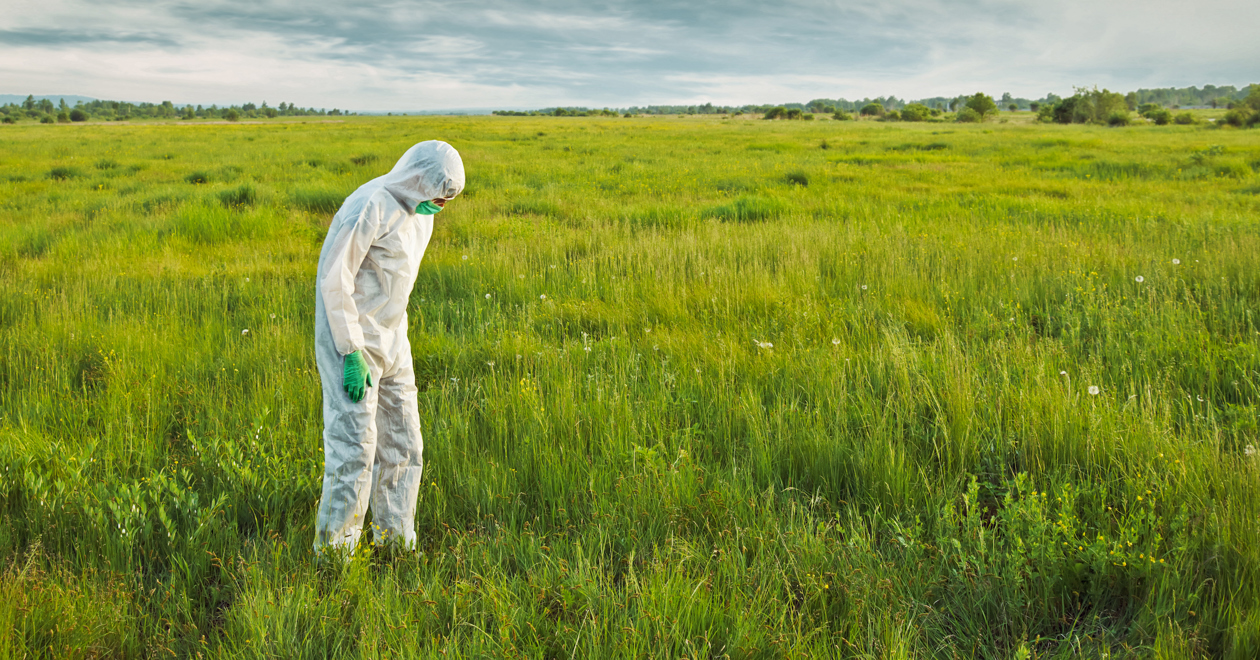 Hazmat guy in a green field