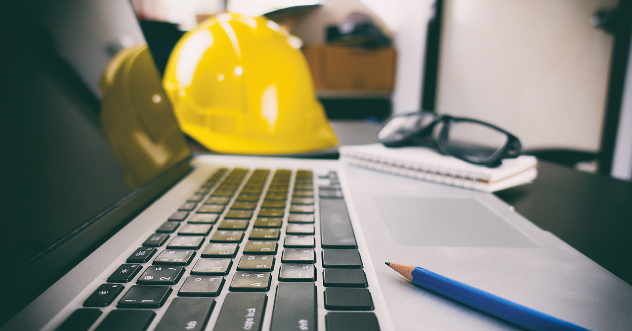 Hard hat, laptop and pencil on desk