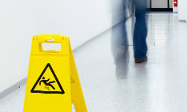A person walking past a slippery surface sign
