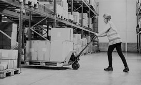 A warehouse worker using a hydraulic piece of lifting equipment to move heavy boxes