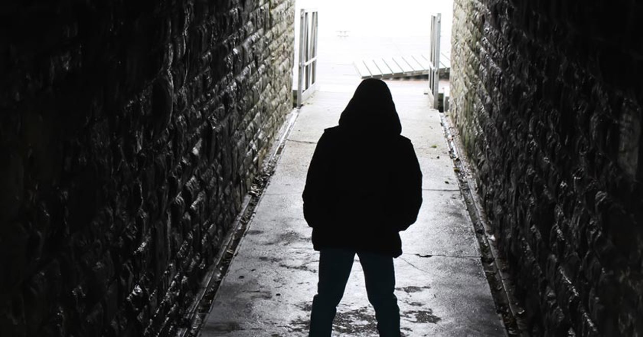 Hooded figure standing in an alleyway