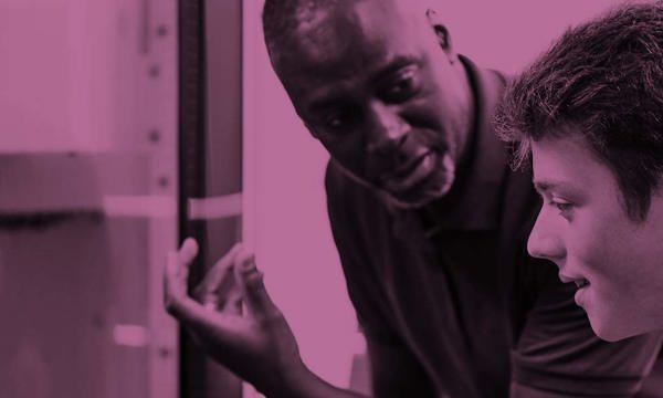 Two people at a computer. One is having something explained to them by the other.