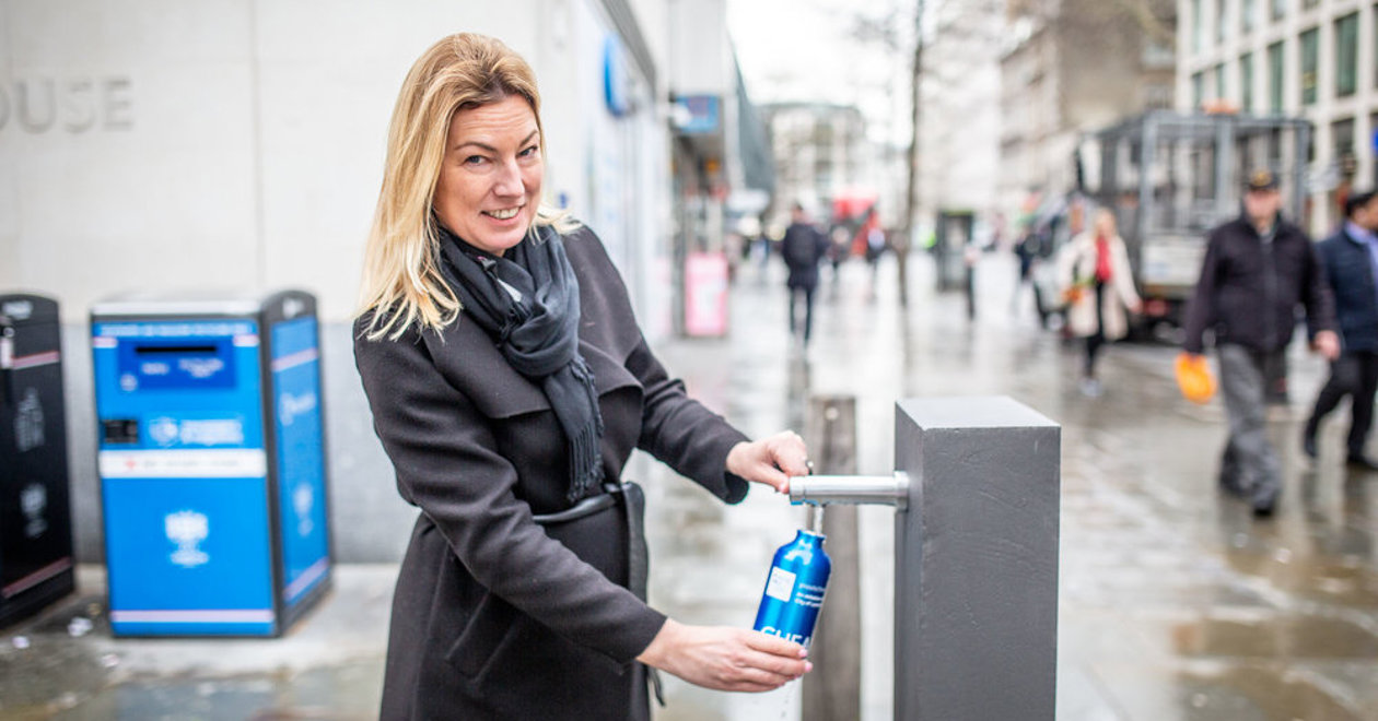 Woman at a new drinking water refill points at Bow Church Yard
