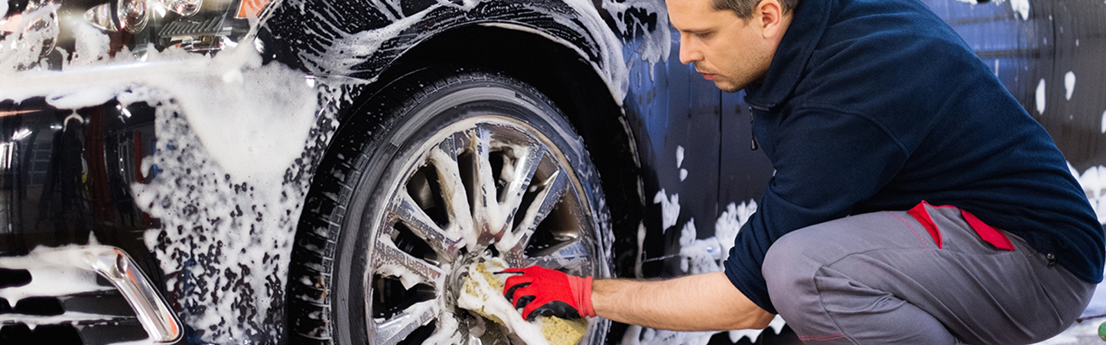 A man washing a car's front wheel