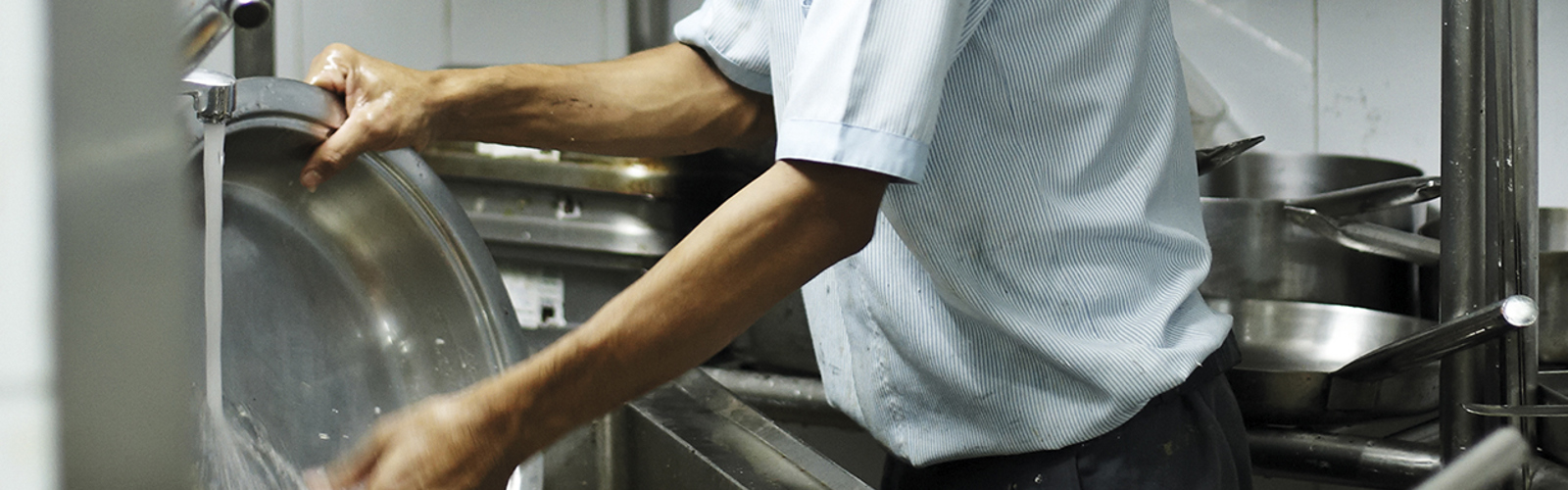 A person washing up in an industrial kitchen