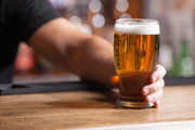 A person's hand holding a pint of beer