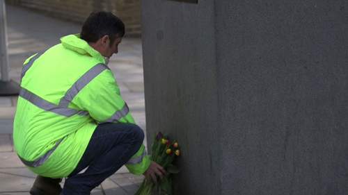 A protester laying flowers at the 'Unknown building worker' statue
