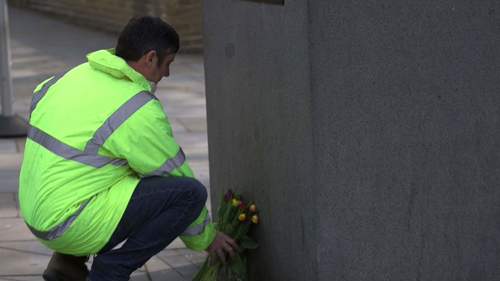 A protester laying flowers at the 'Unknown building worker' statue