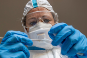Person wearing gloves and a mask holding a sample