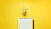 Light bulb above note pad on yellow background