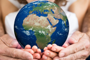 Planet Earth cradled in three pairs of hands