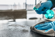 Hands cleaning a surface with spray and a cloth