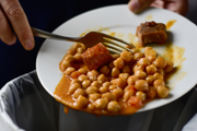 A full plate of food being emptied into a bin