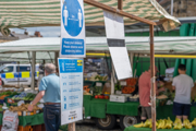 A sign asking for people to maintain social distancing due to COVID-19 at a grocery stall at an outdoor market in Richmond, North Yorkshire