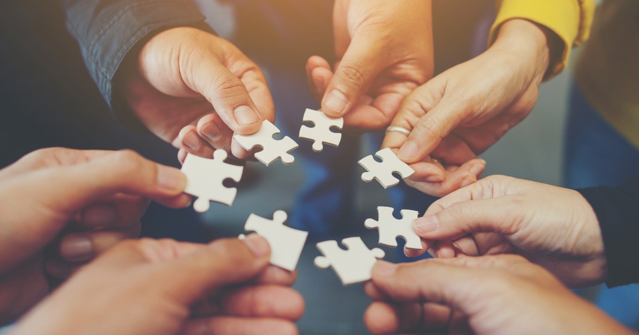Seven individual hands holding puzzle pieces