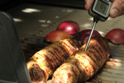 Meat on a grill being probed with a thermometer
