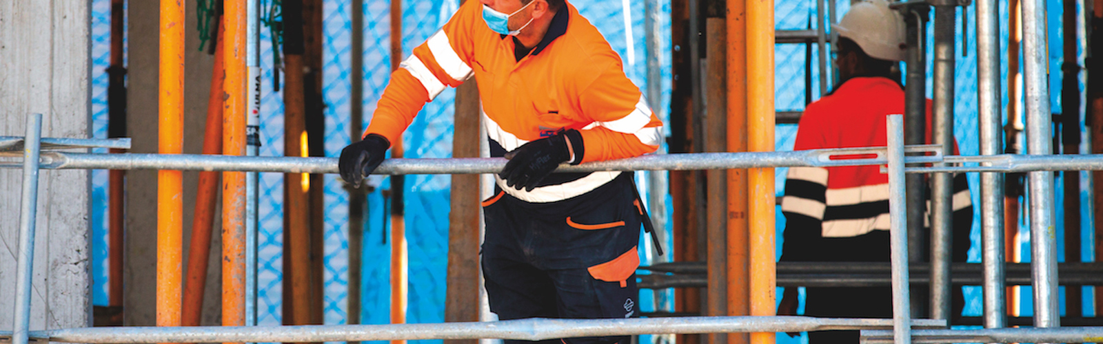 A person in a hard hat and facemask on a building site