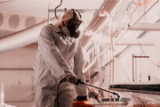 A person in protective clothing spraying a workplace with disinfectant