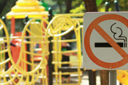 A no smoking sign in front of a children's climbing frame in a playground.