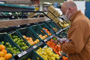 A shopper in a face mask in the fruit section of a supermarket