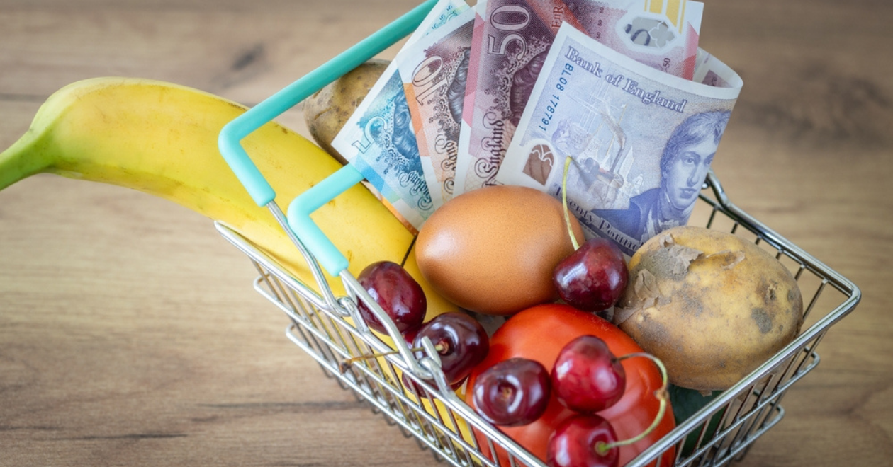 Shopping basket with food and a bundle of English pounds, economic concept, rising inflation and the rising cost of living for British people