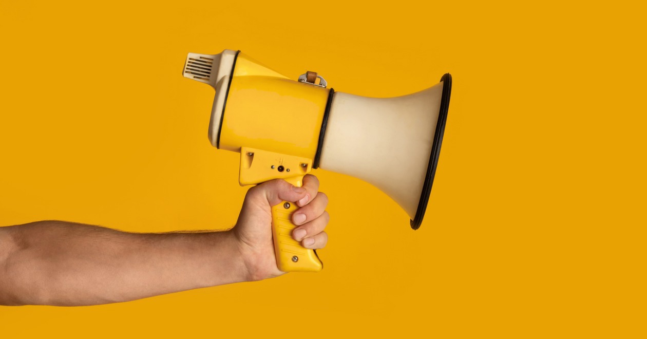 Hand holding a megaphone with yellow background