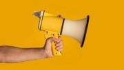Hand holding a megaphone with yellow backgroundCoastal path