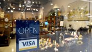 Shop's glass door with sign stating open and uses VISA