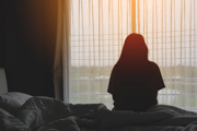 A woman in silhouette in front of a hotel room window