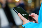 A woman holds a smartphone displaying the Uber logo