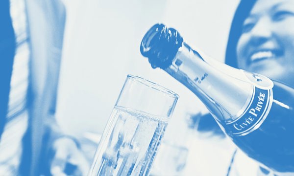 Smiling woman with a drink being poured in the foreground