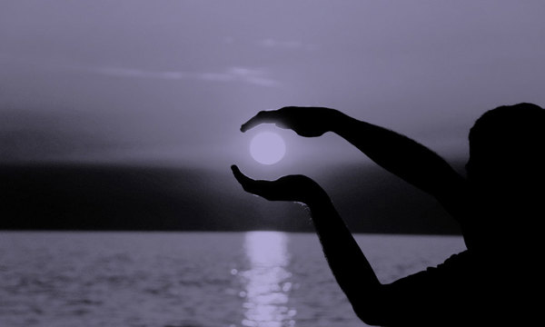 Person holding their hands around the sun