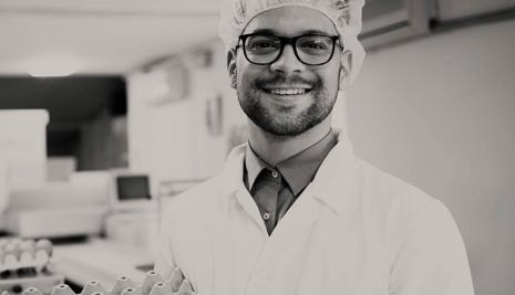 Man in a lab coat holding egg boxes