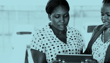 Two woman in conversation looking at a tablet