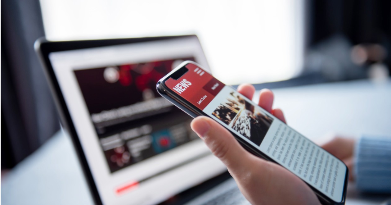 Laptop and mobile phone showing news