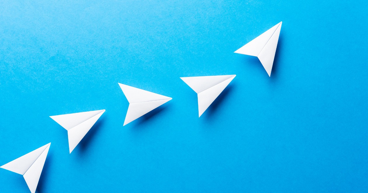 Five paper aeroplanes on blue background