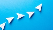 Five paper aeroplanes on blue background