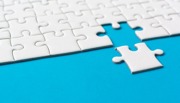 White jigsaw piece completing the puzzle on blue background