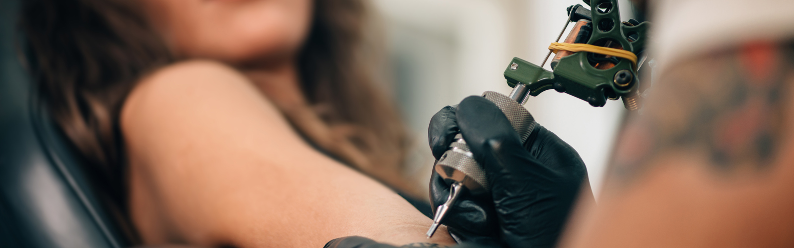 Tattooist tattooing a persons arm