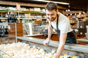 A supermarket worker stacks a fresh produce aisle