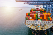 A boat sails past shipping containers