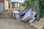 Household items discarded next to row of garages