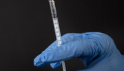 Needle filled with botox held by blue gloved hand